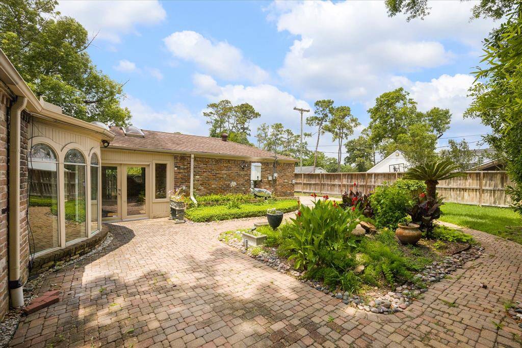Enjoy a fully fenced backyard with winding brick paths, vibrant plantings, and direct access to the breezeway and garage—ideal for relaxing, gardening, or future outdoor upgrades.