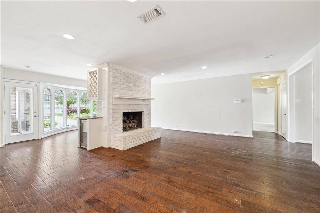 The spacious family room centers around a whitewashed brick fireplace and flows seamlessly into the sunroom, where arched bay windows and backyard views bring in plenty of natural light.