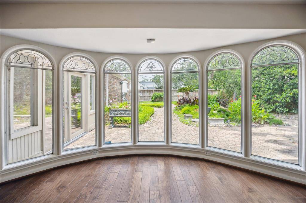 The light-filled sunroom is perfect for morning coffee or quiet afternoons and offers a wall of arched bay windows with decorative transoms that frame tranquil backyard views.