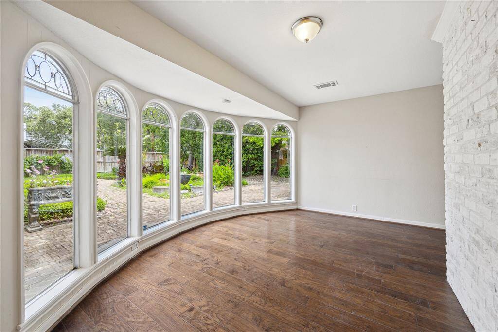 Arched windows and peaceful backyard views fill this sunroom with charm and light, offering plenty of potential to make it your own.