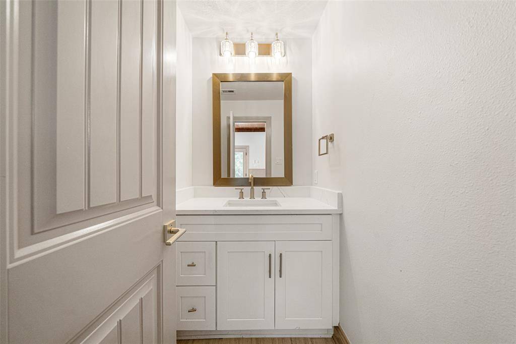 GUEST HALF BATH- Counter is QUARTZ "Calcatta Oslina Gold".  Near the Covered Patio at the Sunroom for convenience. New sink console, plumbing fixtures, lighting, hardware & mirror.
