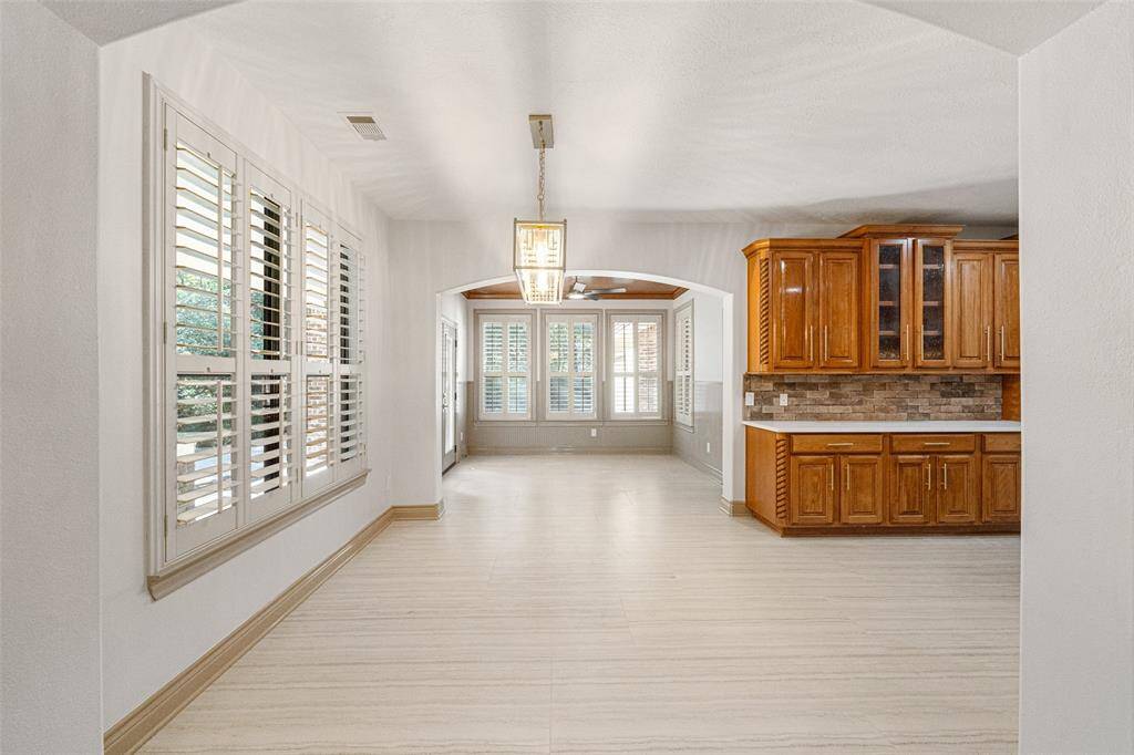 SUNROOM View from Breakfast Area. Looking beyond into the Sunroom with beautiful wooden ceiling accent. New 8 blade fan with integrated light. This is great flex space for Fitness, 2nd Home Office, Playroom, Keeping Room, Library . . .Half Bath access is at Sunroom.