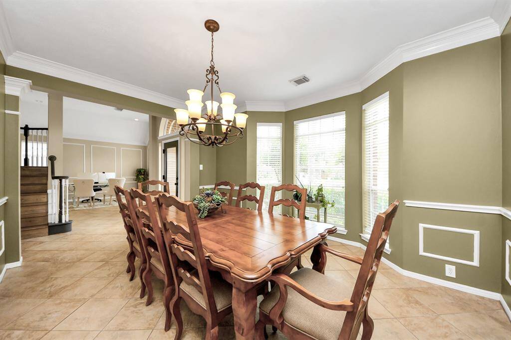 Elegant formal dining room featuring a bay window that fills the space with natural light. Beautiful crown moldings add a touch of refined architectural charm.