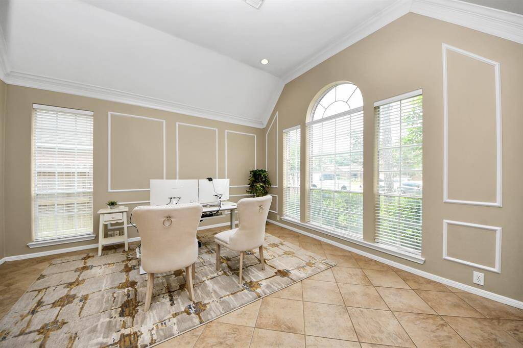 Spacious formal living room with soaring ceilings and large windows offering serene views of the front lawn. This versatile space is perfect as-is or can be effortlessly transformed into a private study with the addition of French doors.