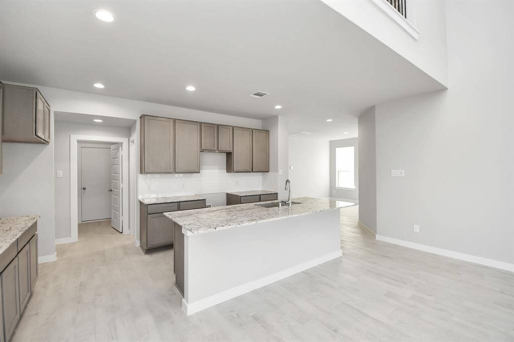 Discover another perspective of this stunning kitchen, sleek back splash, single basin sink, and generously appointed with an abundance of counter space. Sample photo of completed home with similar floor plan. Actual colors and selections may vary.