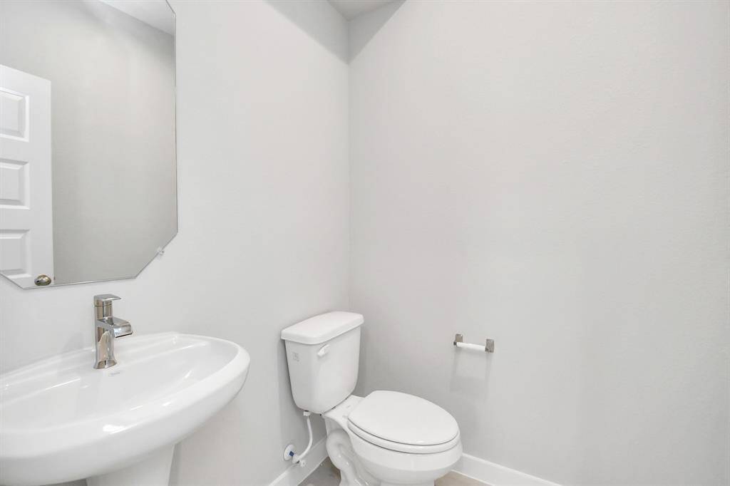 The half bathroom, conveniently situated on the 1st floor, is adorned with contemporary finishes. Custom wall paint, and a sleek faucet combine to create a bright and inviting space. Sample photo of completed home with similar floor plan. Actual colors and selections may vary.