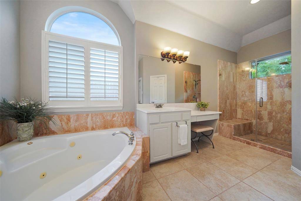 Gorgeous tile surrounds the large walk in shower with bench as well as the spa tub. Glass shower doors/surround.