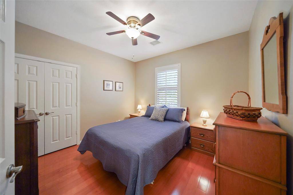 One of the secondary bedrooms. All of the secondary bedrooms are spacious with wood look flooring, ceiling fans and shutters.