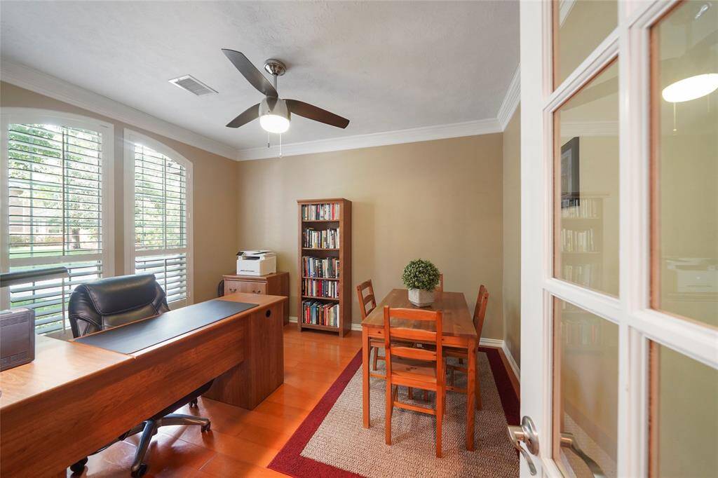 The private office overlooks the lush front yard with large windows. Shutters, ceiling fan, French doors and wood  flooring.