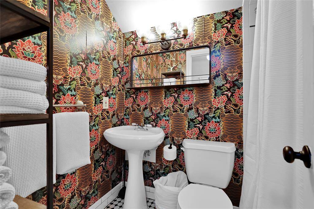 New stylish wallpaper, light fixtures, mirror, and shower in the secondary upstairs full bath