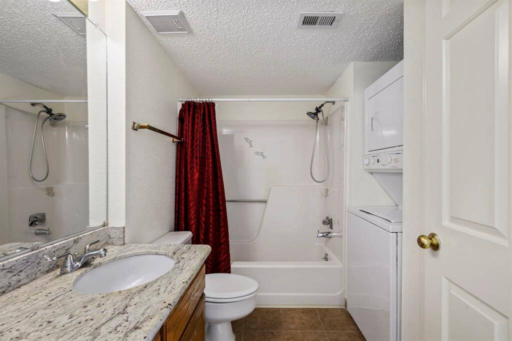 Primary Bathroom - Granite counter, tub with shower and stackable washer dryer combo.
