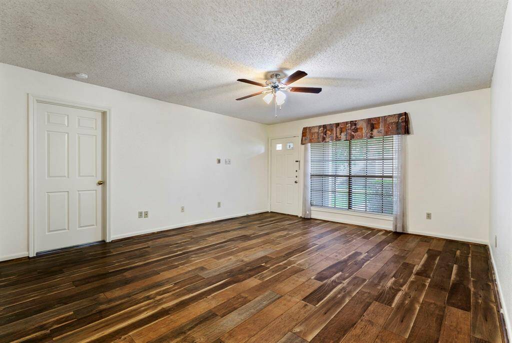 15x14 Living Room - Looking toward the front door and view through the window shows the front porch and outdoor landscaping. Door to the left opens to the primary bedroom.