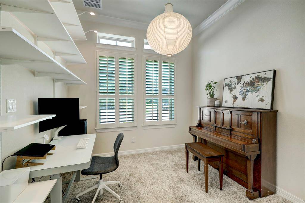 Upon entry, you will be warmly welcomed by a generously sized study room featuring lofty semi-coffered ceilings, enhanced by double crown moldings. The room is thoughtfully embellished with built-in shelving, providing ample storage space, and complemented by cozy carpeted floors.