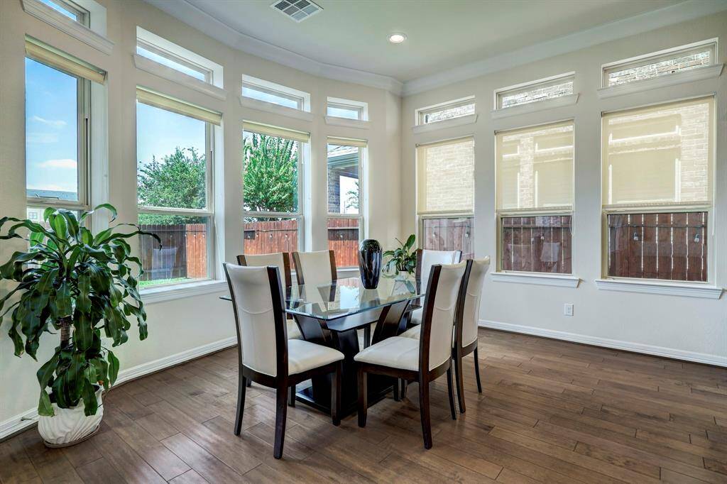 The formal dining room is enveloped by window panels, inviting abundant natural light and providing serene views of the verdant backyard.