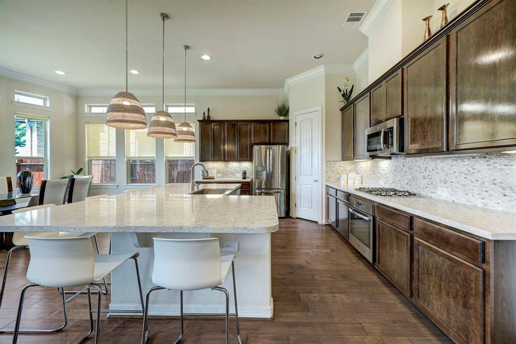 With its quartz counters and modern white quartz backsplash this kitchen offers a fresh air of soft contemporary feel throughout. With its lovely hardwood floors, exquisite dark wood cabinetry, ample lighting, and neutral palette, this kitchen will undoubtedly inspire and excite you to create your own culinary masterpieces.