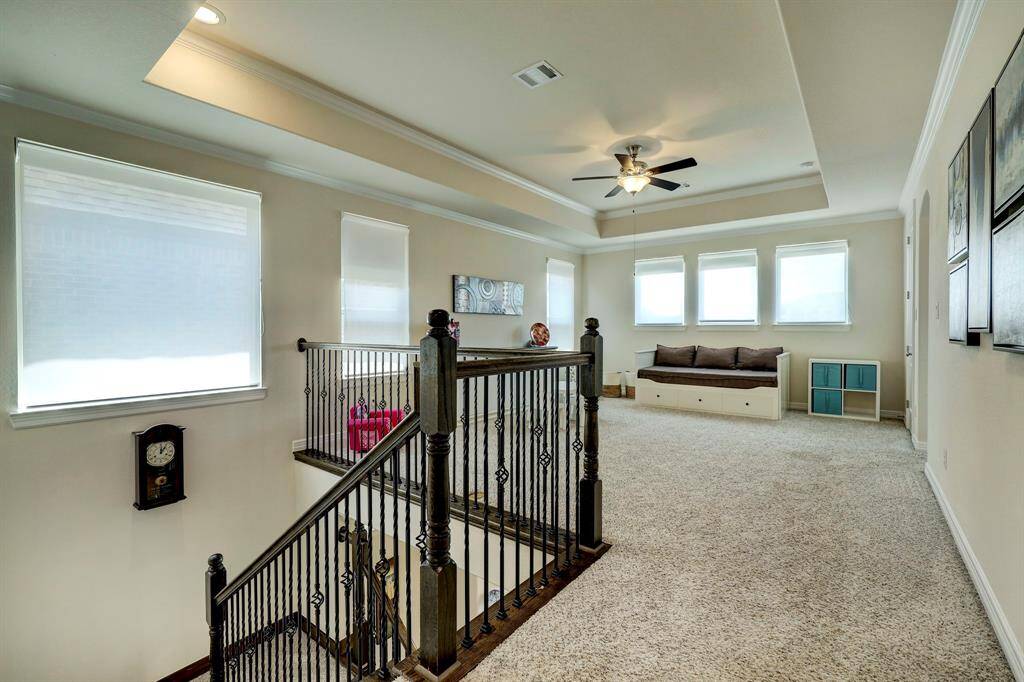 The second-floor landing leads you to the gameroom. It features an impressive recessed ceiling adorned with double crown moldings, large window panels that fill the space with natural light, comfortable carpeted floors, and a pleasing neutral color palette. It conveniently provides direct access to the upstairs game room, which also serves as a versatile common area.