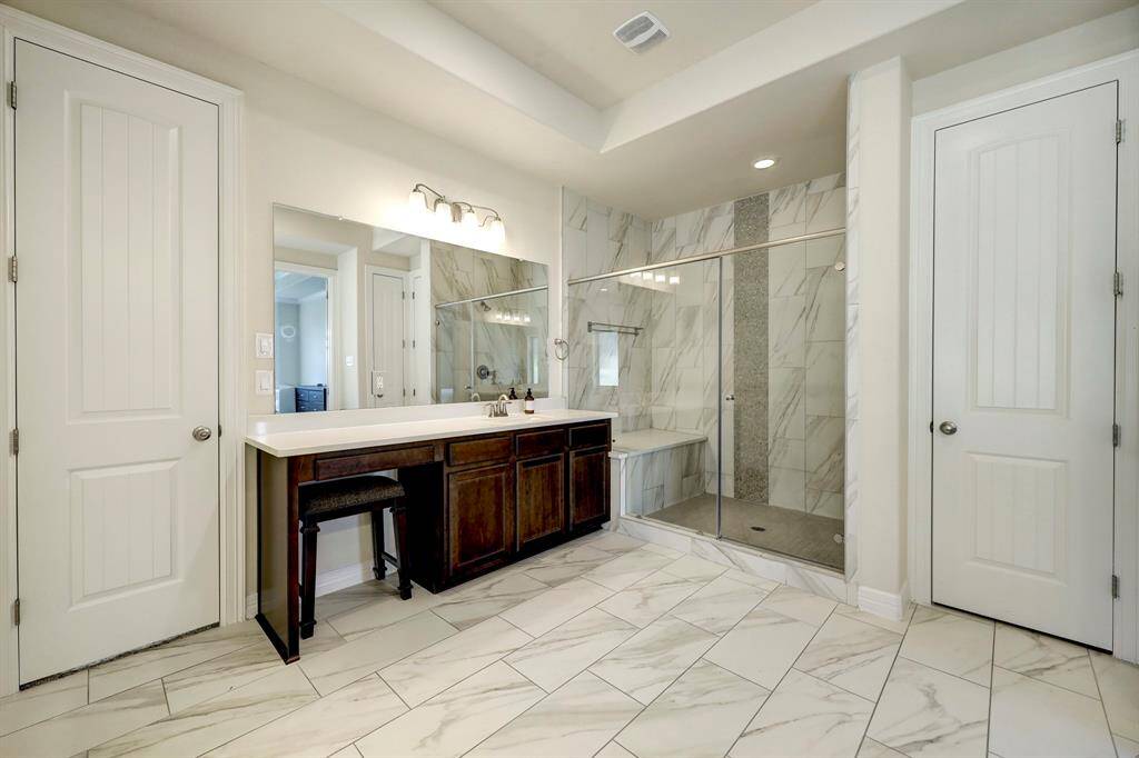 The bathroom offers a spacious glass enclosed shower with bench for your convenience.