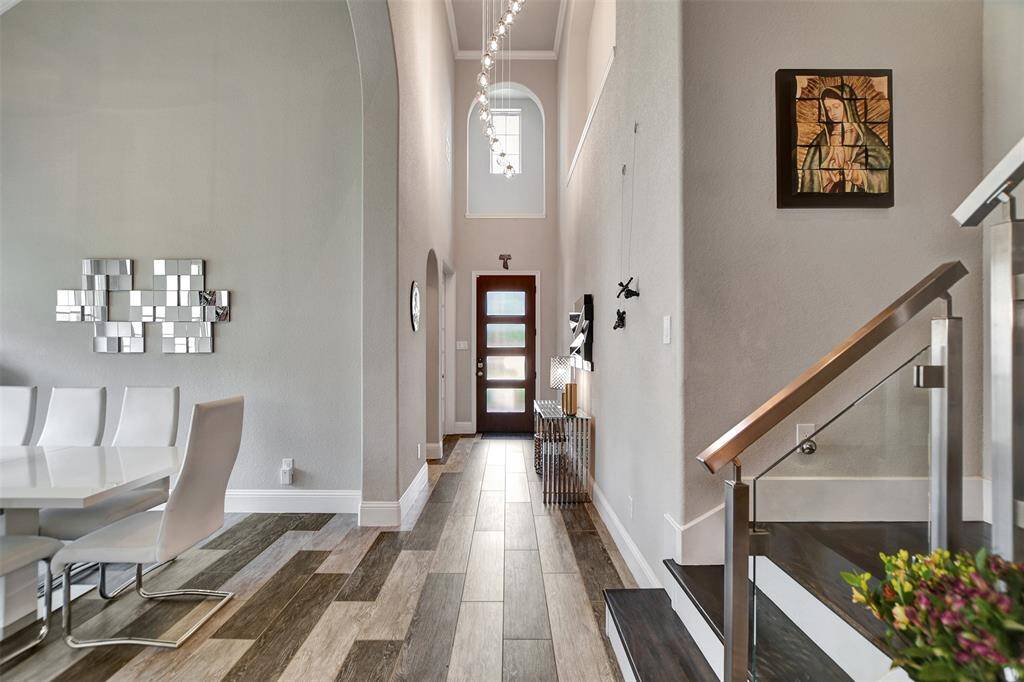This inviting foyer features high ceilings and a stylish lamp, with a staircase leading to the upper level. As you enter to the right open into the home office, while the hallway leads to a bright living area with large windows. The space is modern and welcoming, ideal for a family home.