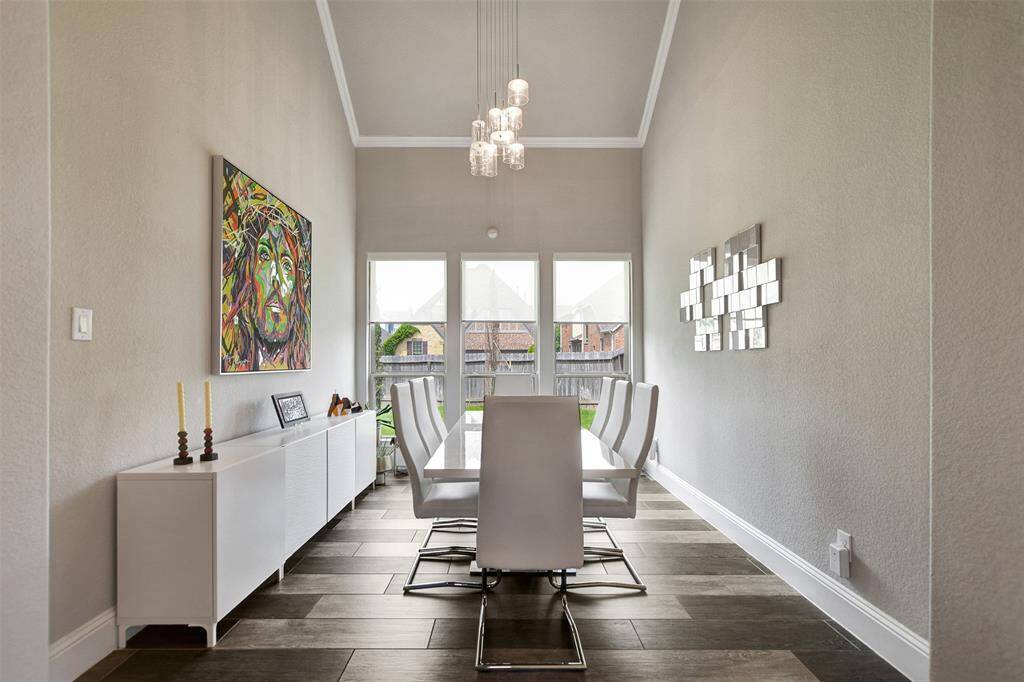 This elegant dining room has ample space for your next gathering. It features a stylish lamp, creating a sense of flow and spaciousness.
