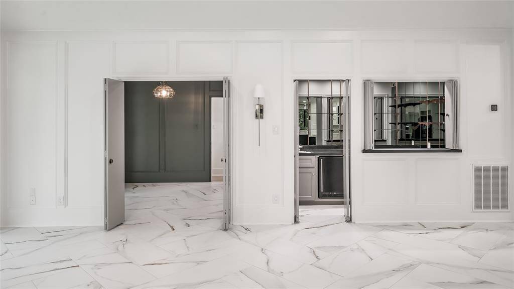Home beverage bar adjacent to the great room features a sink, beverage cooler, built-in cabinets and counters, and glass shelving. This room can be closed off when not in use and opened when entertaining.