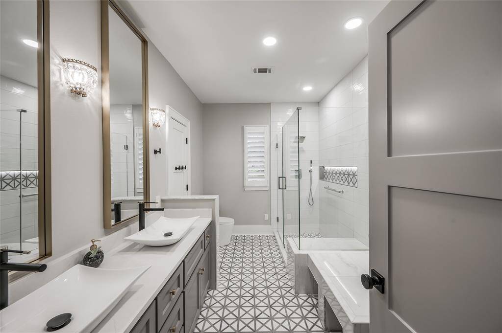 Secondary bathroom features a dual vanity and large glass walk-in shower.