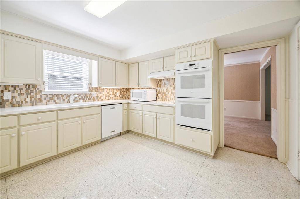 This view of the kitchen highlights the double ovens and offers a clear line of sight into the formal dining room. To the right, a spacious walk-in pantry provides ample storage and easy access to everyday essentials.
