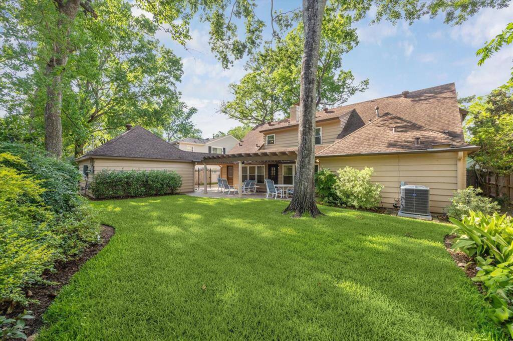 This alternate perspective showcases the backyard’s generous size and thoughtful layout, highlighting open grassy areas perfect for play or relaxation. Mature trees and lush landscaping frame the space, creating a private and inviting atmosphere that seamlessly connects with the home’s outdoor living areas. Whether hosting gatherings or enjoying quiet moments, this backyard offers ample room to make lasting memories.