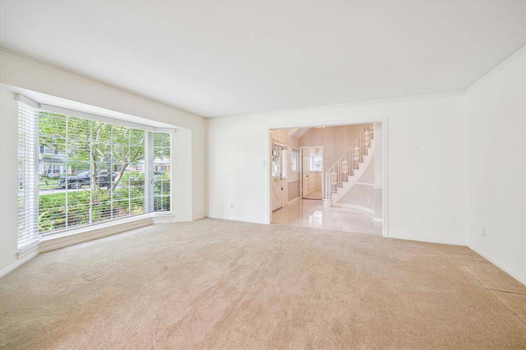 The formal living room offers a panoramic view of the front yard, inviting nature's beauty indoors through expansive windows. Open to the formal dining area, it seamlessly blends elegance with functionality, creating a space perfect for both intimate gatherings and grand celebrations.