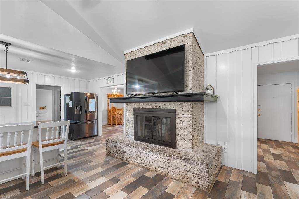Spacious and sun-filled — this cozy living room is the heart of the home, featuring a wood-burning fireplace and no carpet throughout.