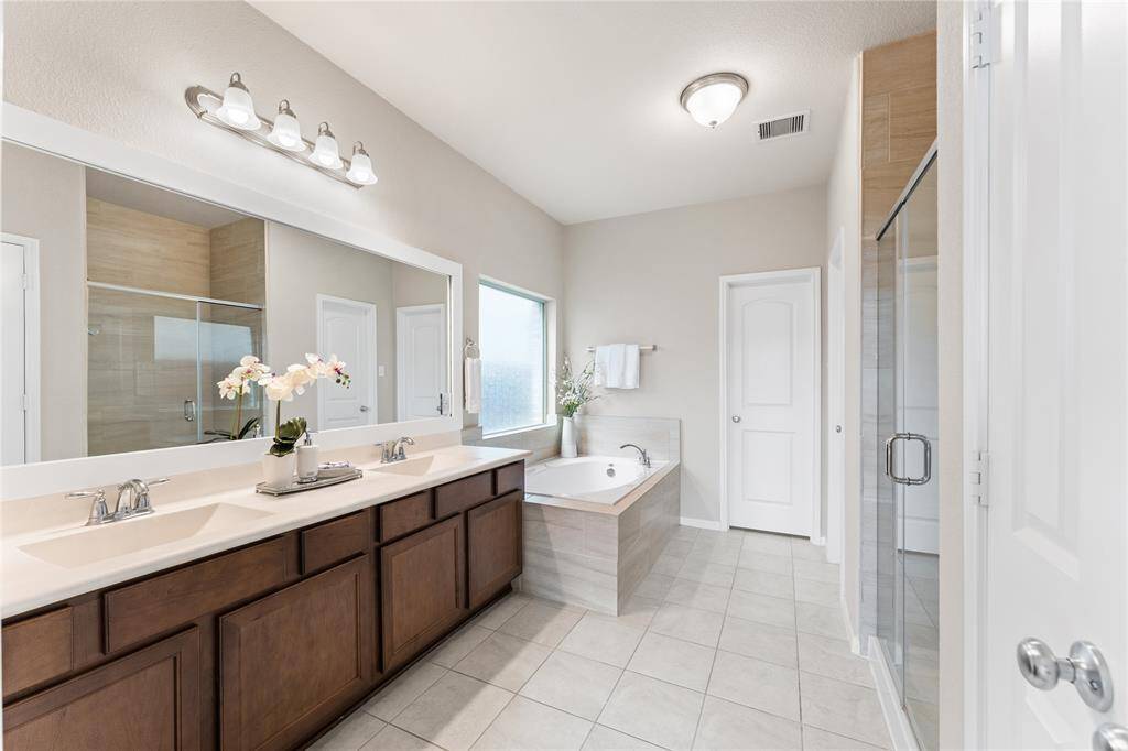 Enjoy spa-like comfort in the en suite bath, complete with double vanities, a large soaking tub, and a separate glass-enclosed shower.