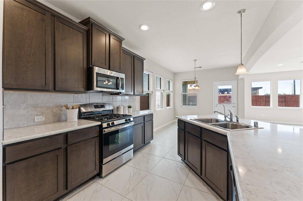 The kitchen is a chef’s dream with abundant cabinetry, sleek stainless steel appliances, and sprawling countertops.