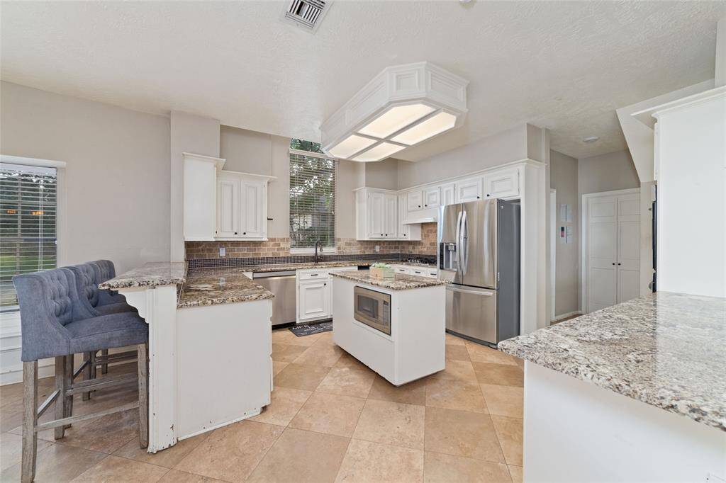 Kitchen opens to family room with bar area and access to utility room and dining room