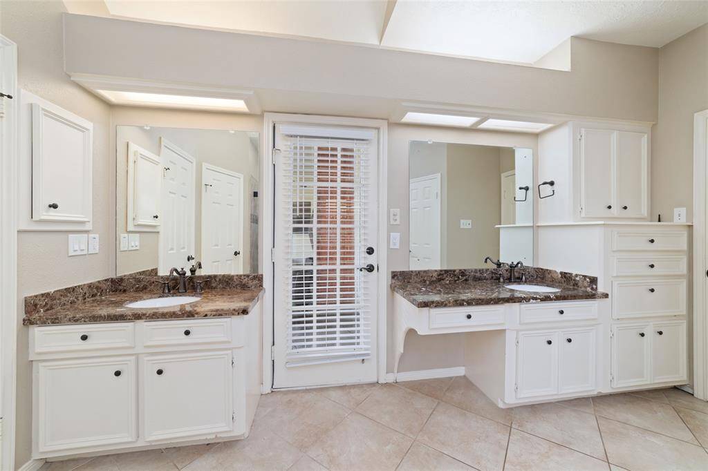 Primary bathroom with double vanity and door access to the back patio