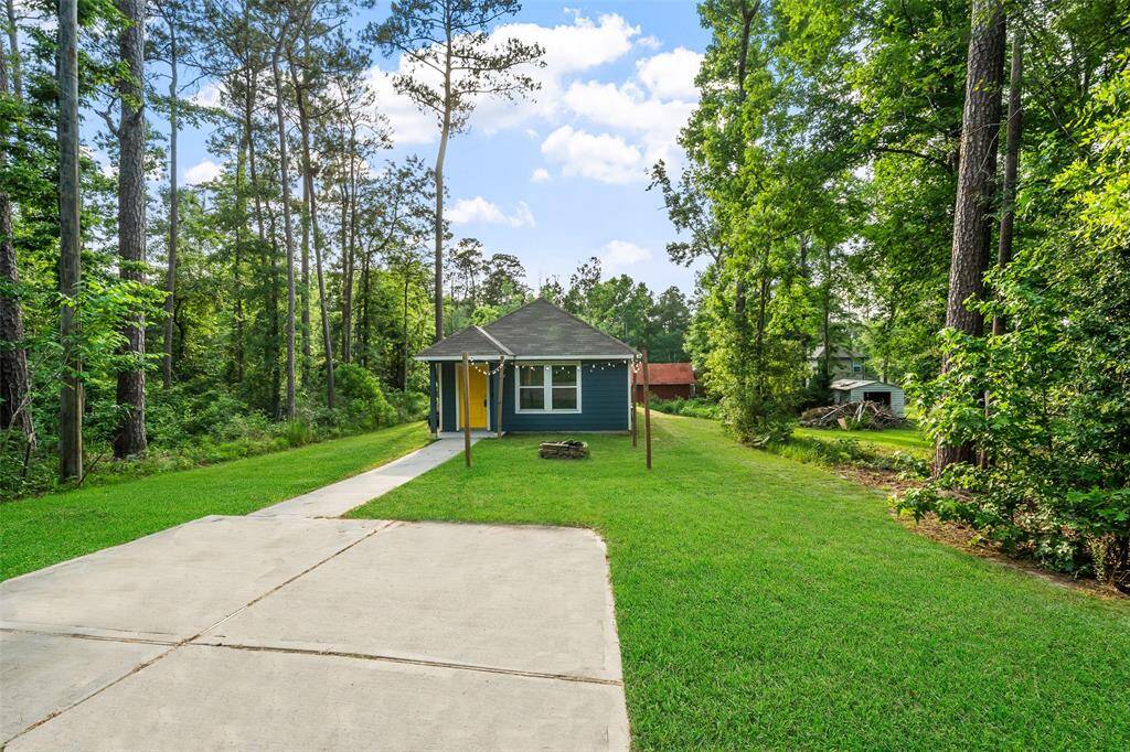 Quaint front yard with firepit! Concrete pad has parking for 2 cars. *Grass has been digitally altered*