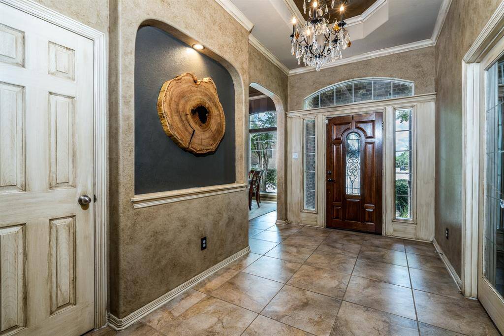 Looking towards the front door from the entryway. Large hall closet, formal dining room and office/study. Notice the lovely chandelier and elegant tray ceilings that greet you with luxury as you enter the home.