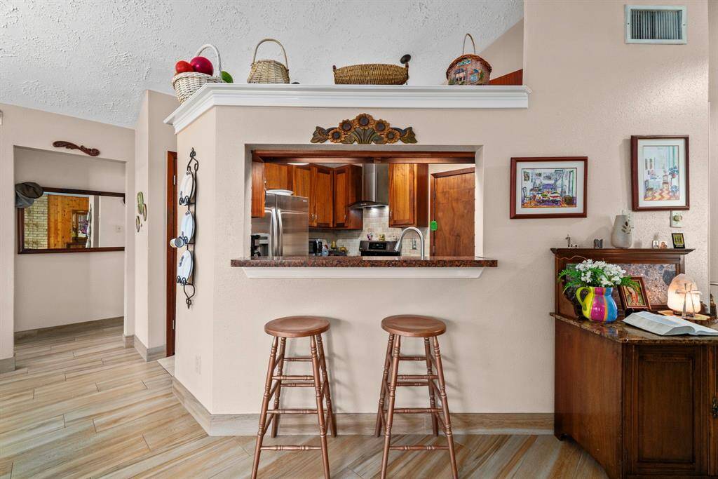 A breakfast bar features a window that provides a view into the updated kitchen.