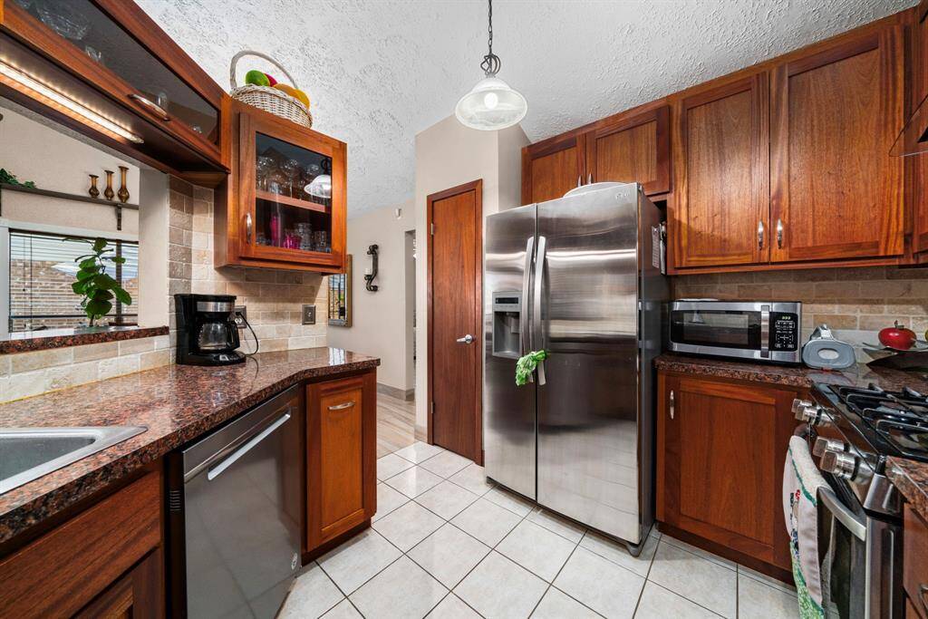 Fabulous remodeled kitchen with custom cabinets, stainless steel appliances, a stylish vent hood, elegant countertops, a chic backsplash, and more.