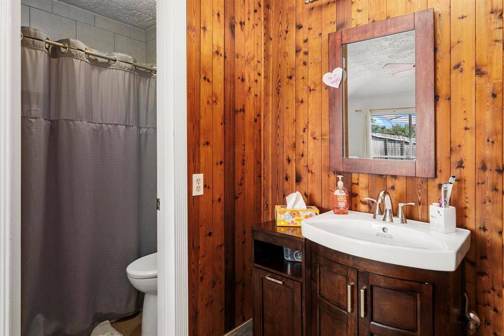 Primary bathroom showcasing elegant wood-accented walls and a stylish freestanding vanity. It also includes a spacious updated walk-in shower.