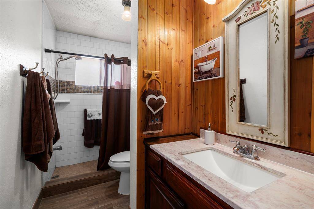 The second full bathroom features a charming wood accent wall, an updated vanity, and a spacious walk-in shower.