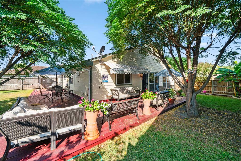 Spacious backyard with a wrap-around wooden deck, ideal for multiple seating areas.