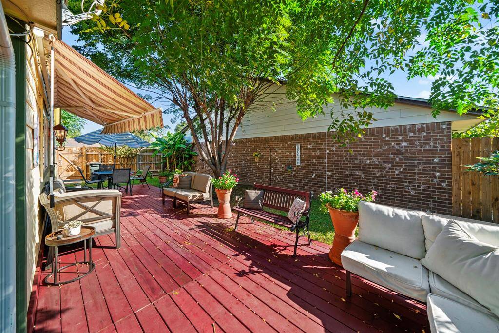 Spacious backyard with a wrap-around wooden deck, ideal for multiple seating areas.
