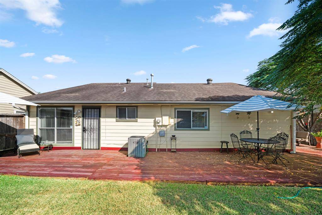 Spacious backyard with a wrap-around wooden deck, ideal for multiple seating areas.