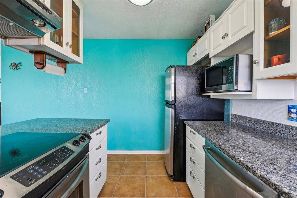 Bright and inviting living space featuring a modern chandelier, hardwood floors, and a cozy fireplace. The room is accentuated by a turquoise wall, large windows with water views, and French doors leading to an outdoor area. A stylish bar table with stools adds a functional dining space.