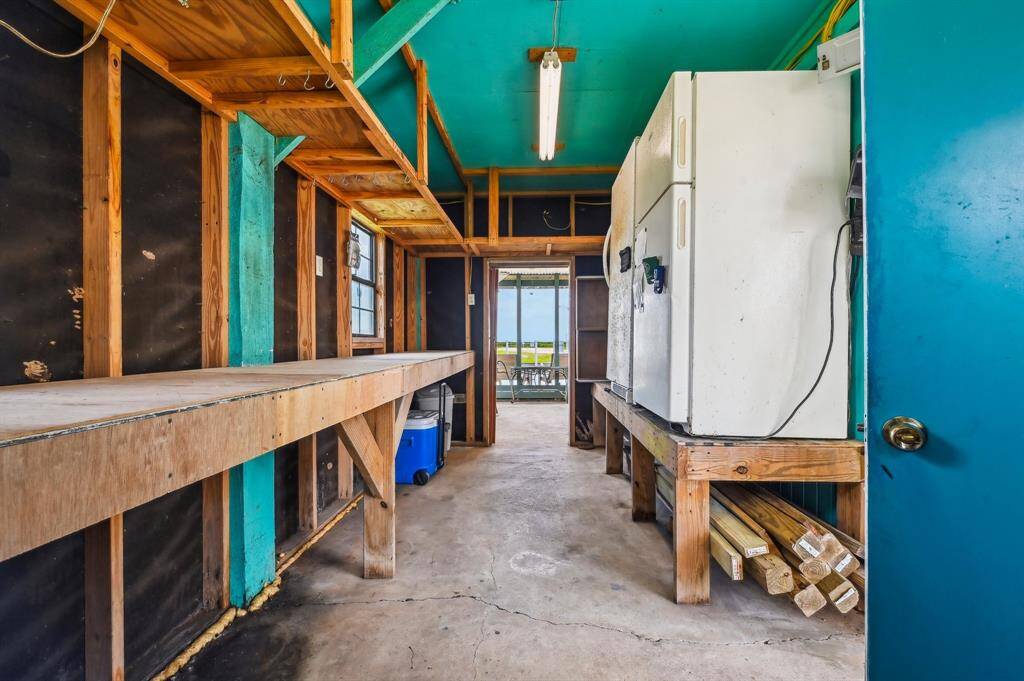 Spacious bedroom with vibrant turquoise walls, featuring a wooden bed with a blue comforter, hardwood floors, and large windows offering plenty of natural light and outdoor views.