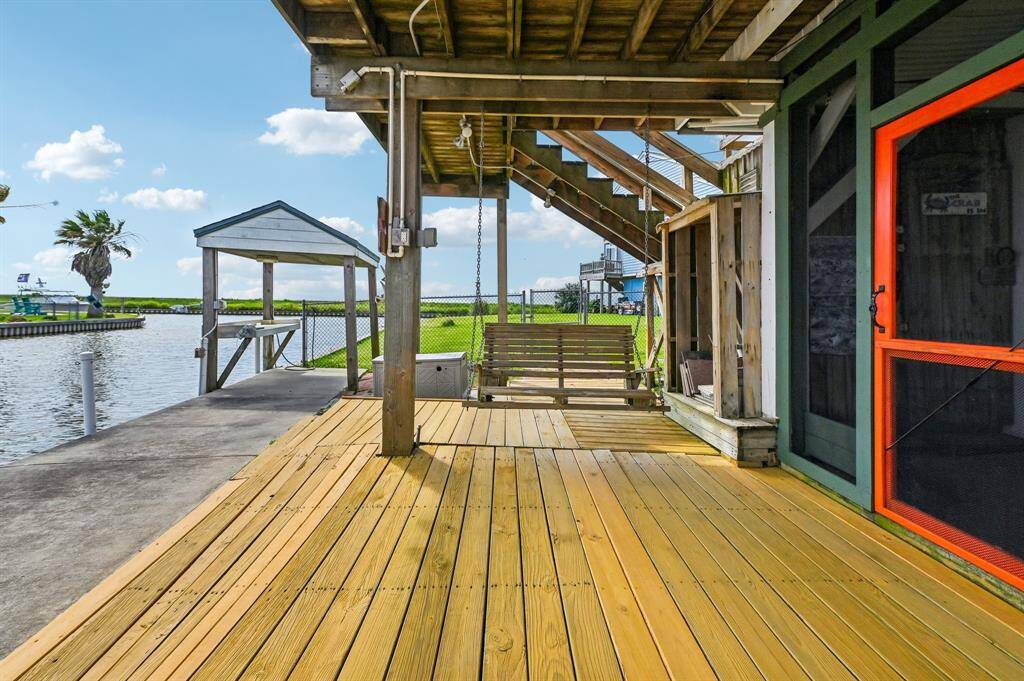 This photo showcases a balcony with a white railing offering a scenic view of a canal and lush green landscape. The space is adjacent to a cozy interior with sliding glass doors, perfect for enjoying peaceful outdoor moments.