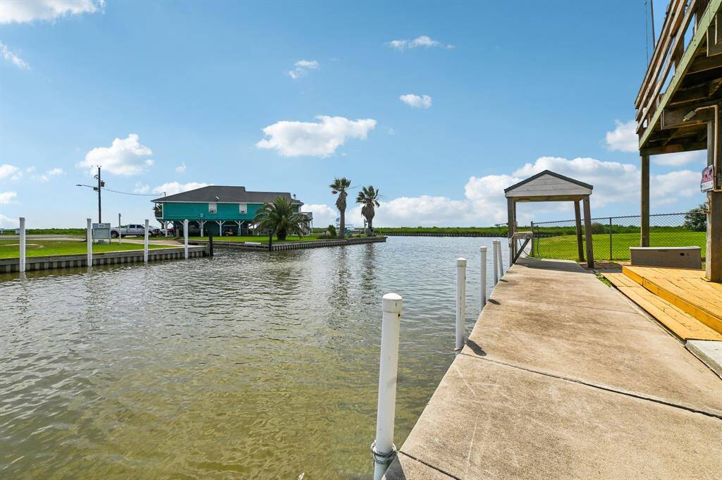 This photo showcases a waterfront property with a spacious wooden deck, a swing, and a covered boat dock. The area offers direct access to the water, making it ideal for boating enthusiasts and outdoor relaxation.