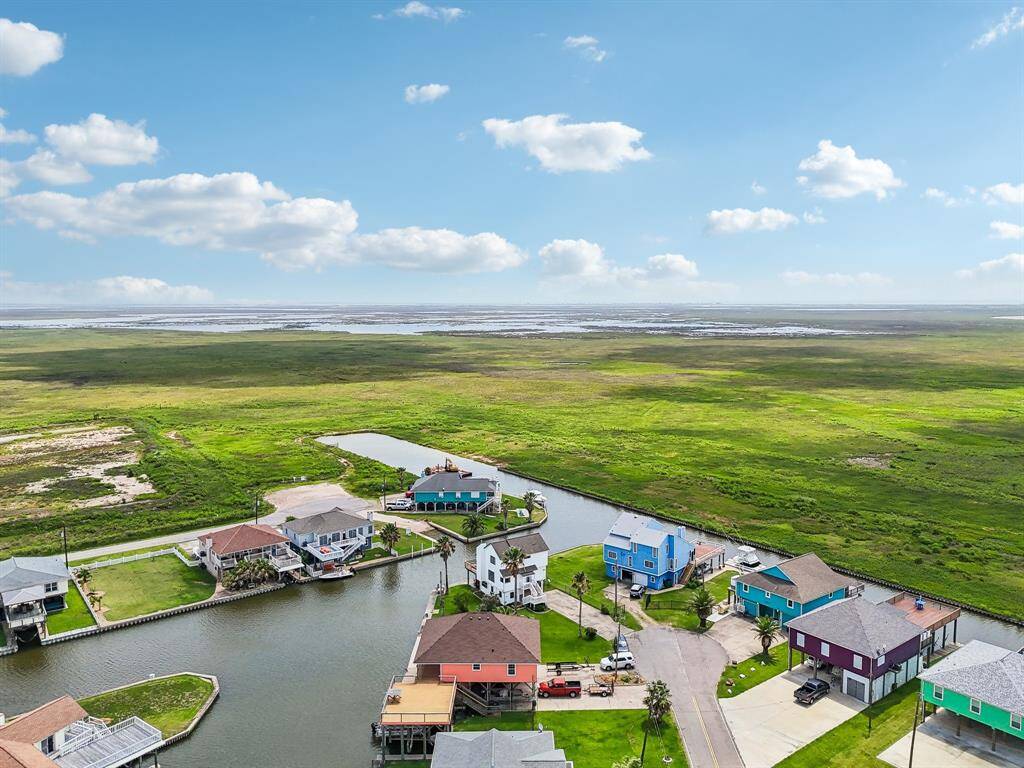 This photo showcases a serene waterfront neighborhood with homes lining both sides of a wide canal, clear skies, and calm water, ideal for boating and enjoying peaceful views.
