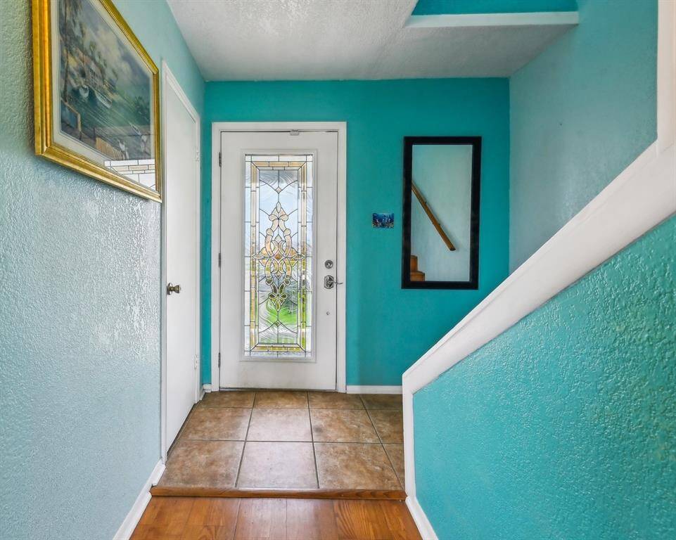 This coastal home features a raised structure with a spacious driveway and lush green lawn. It's surrounded by palm trees and offers waterfront views, perfect for enjoying stunning sunsets.