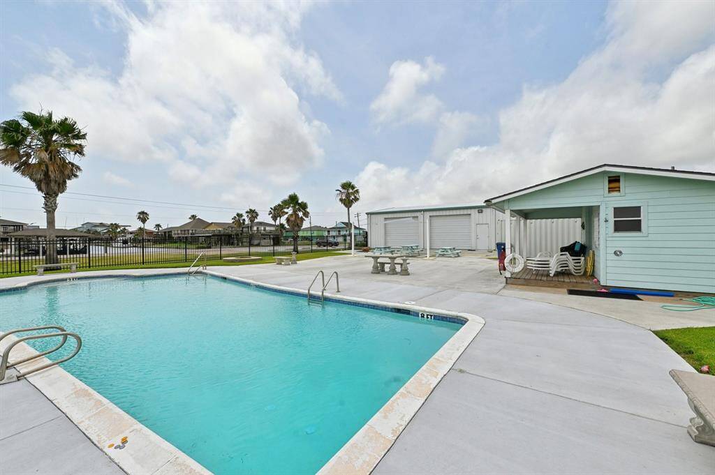 Spacious backyard with a swing set, perfect for families. It features a fenced area, open grassy space, and a couple of palm trees, creating a welcoming outdoor environment.