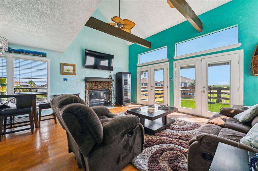 Bright entryway with vibrant teal walls, decorative glass front door, and a mix of tile and wood flooring. A mirror and framed artwork add character, with stairs leading up.